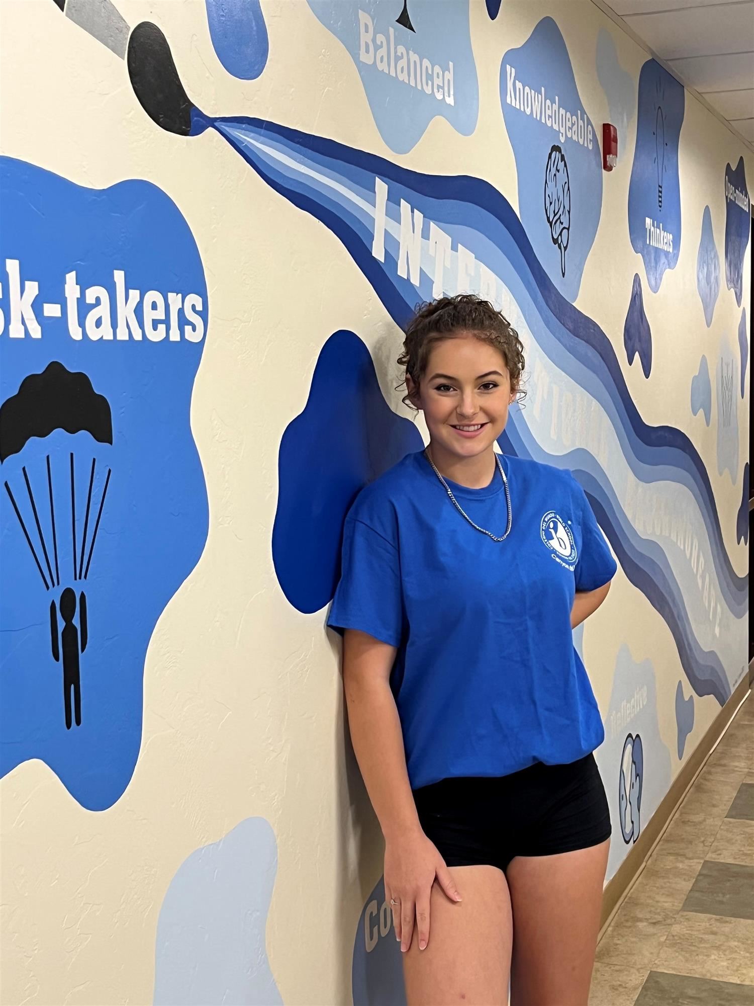 student with IB mural